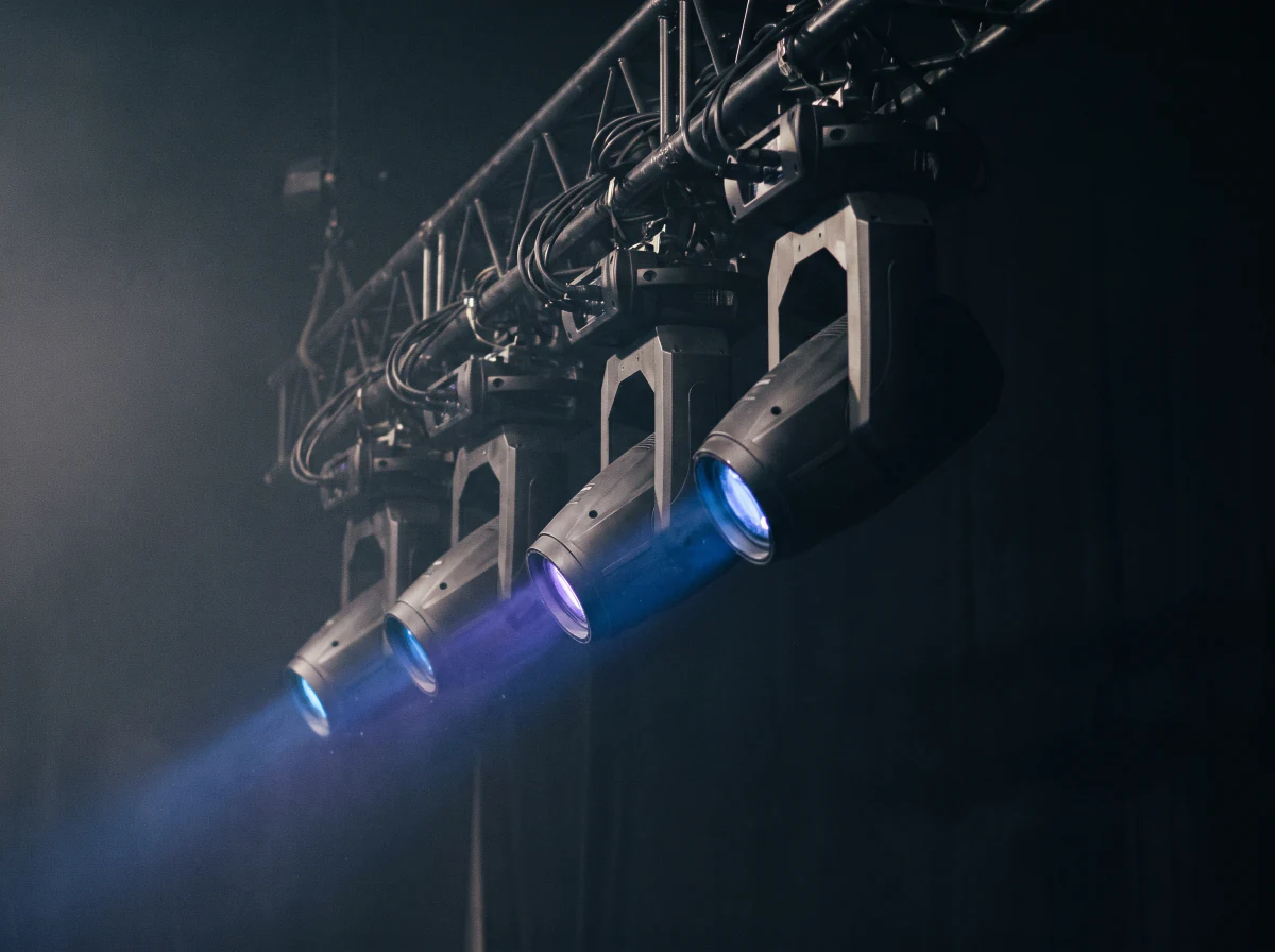Moving-head fixtures on truss throwing beams into haze