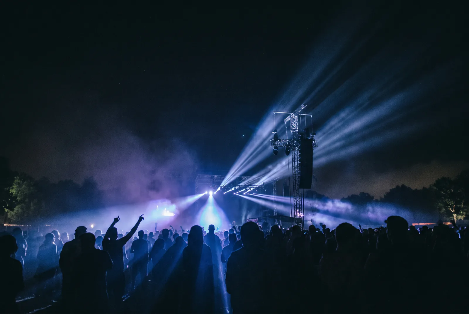 Outdoor night event with beams over the crowd